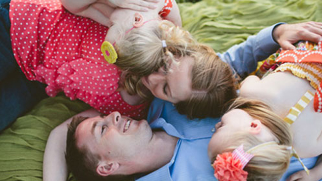 two adults and two children lying on a blanket